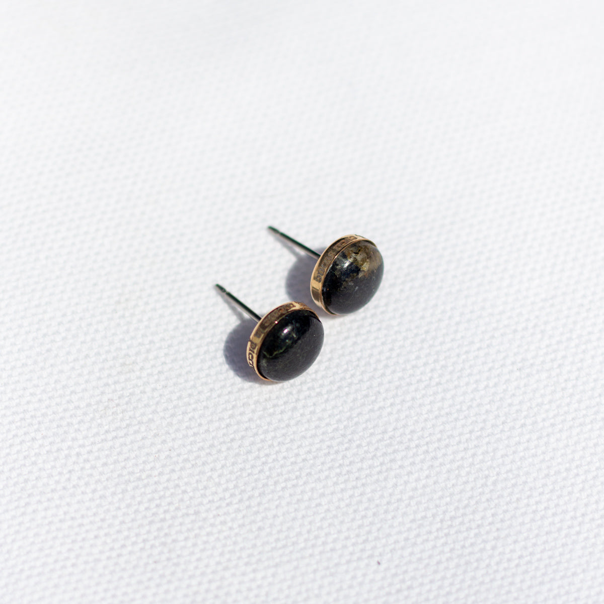 Pair of black stone stud earrings with a 14k gold fill setting on a white background