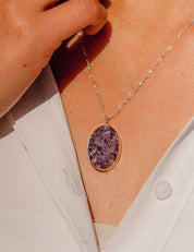Large purple quartz pendant necklace worn by a model in a white oxford shirt