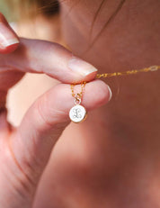 Detail shot showing the back of the pendant, which is engraved with an initial L in a curly, decorative font.