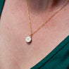 A small round 14k gold pendant engraved with a custom illustration