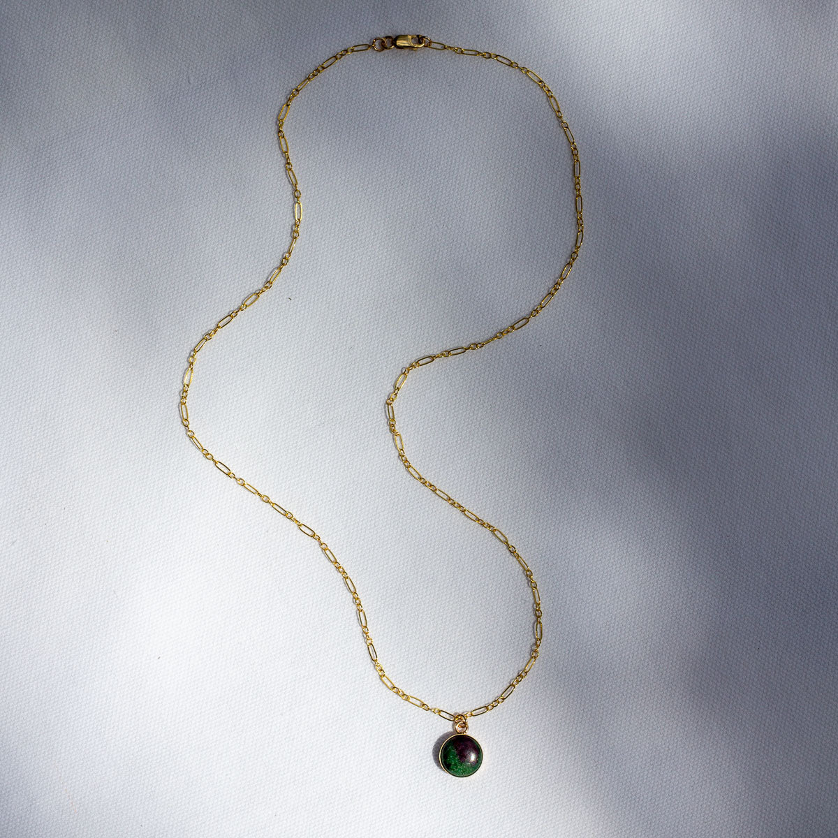14k gold necklace with a delicate chain and a charm made out of a natural stone