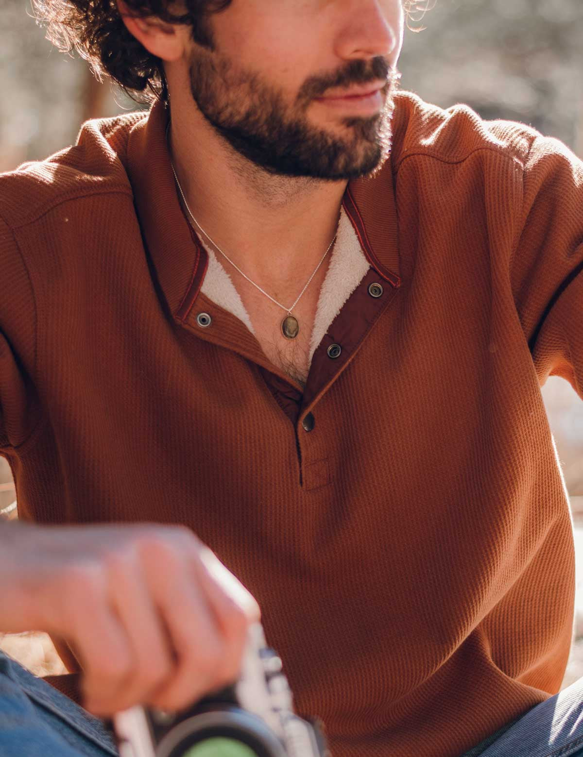 Man wears a choker with a small green oval pendant made of natural stone
