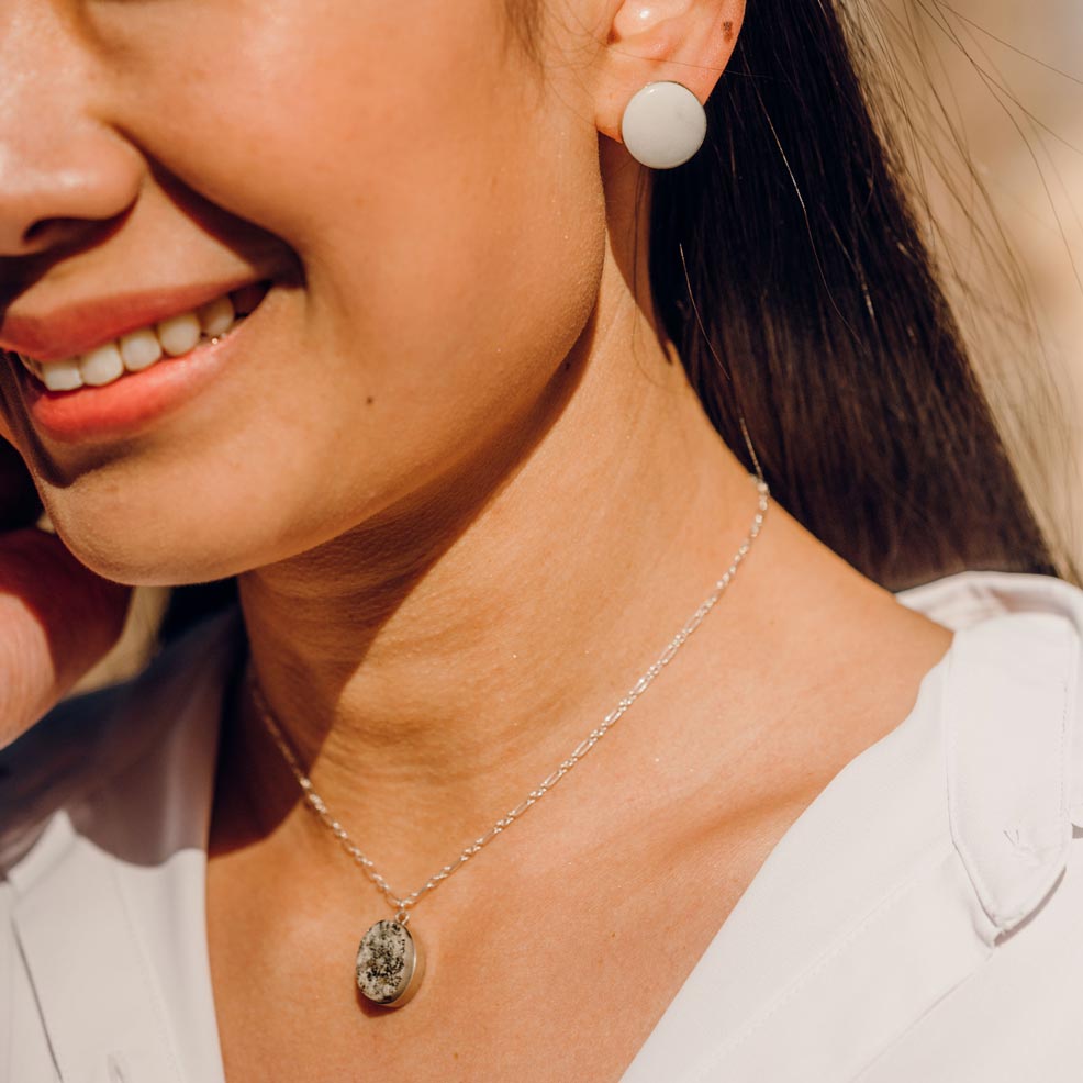 Woman wearing white stone earrings with matching stone necklace