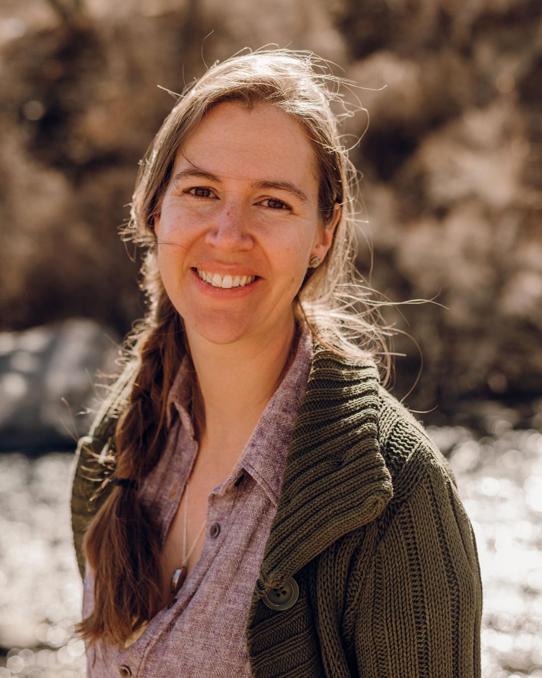 Our co-founder, Leslie, smiling at the camera outside by a river