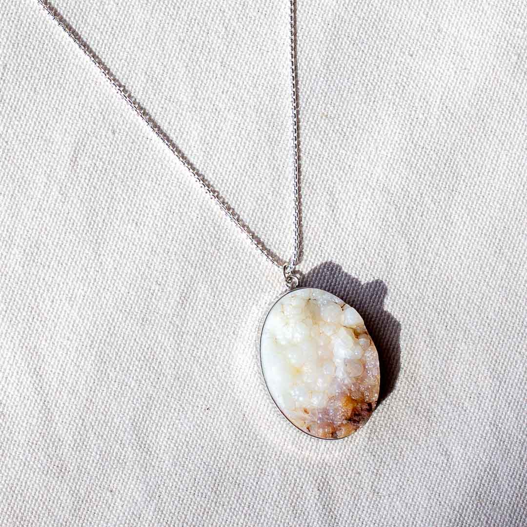 Cream-colored natural stone with an uneven surface set as a sterling silver pendant necklace