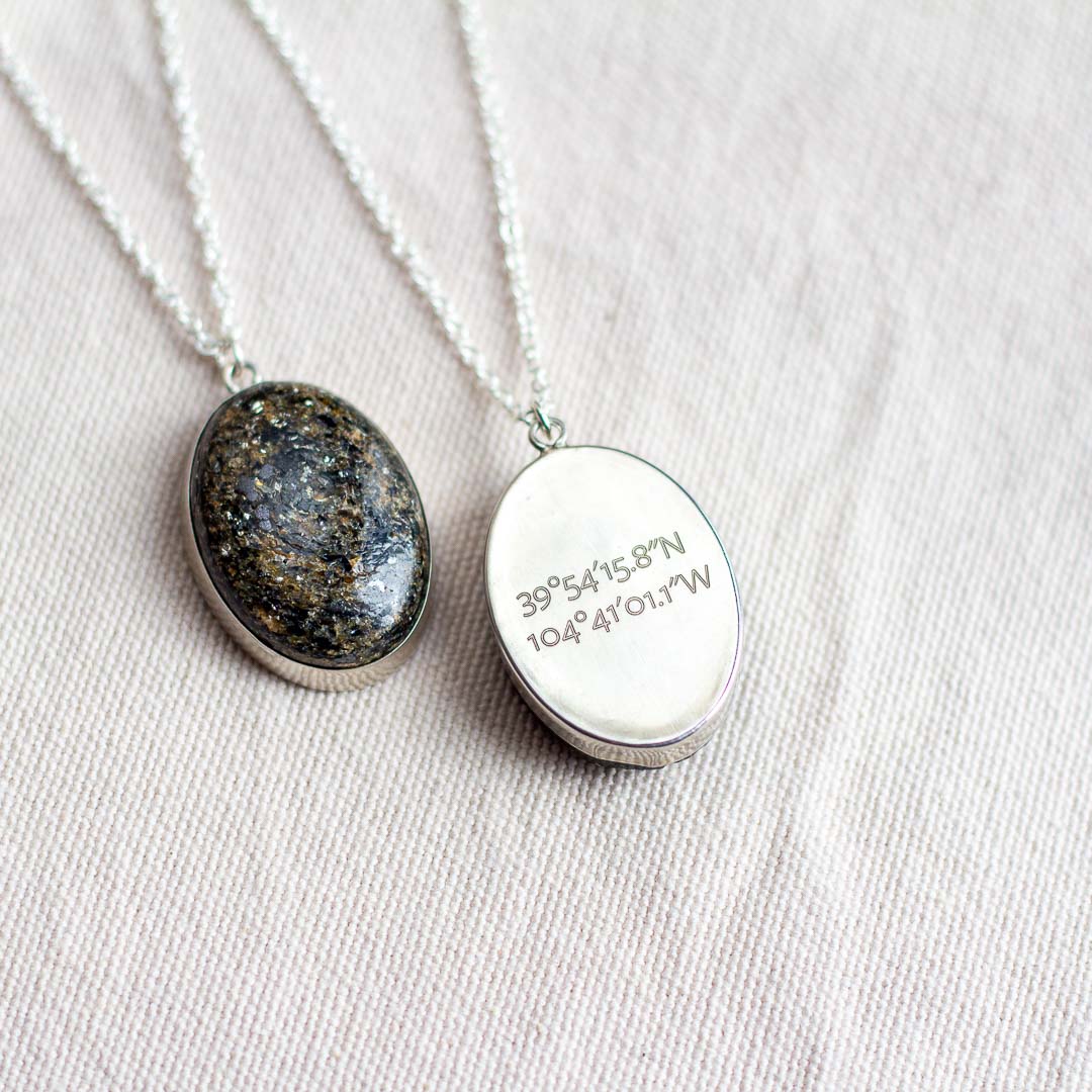 Speckled natural stone pendant set in sterling silver, engraved with latitude and longitude coordinates on the back
