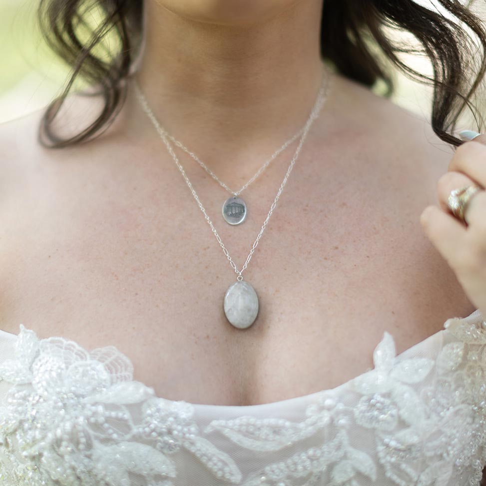 A bride wears a long pendant necklace made of white quartz