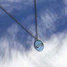 A silver choker with a charm engraved with an illustration of a mountain