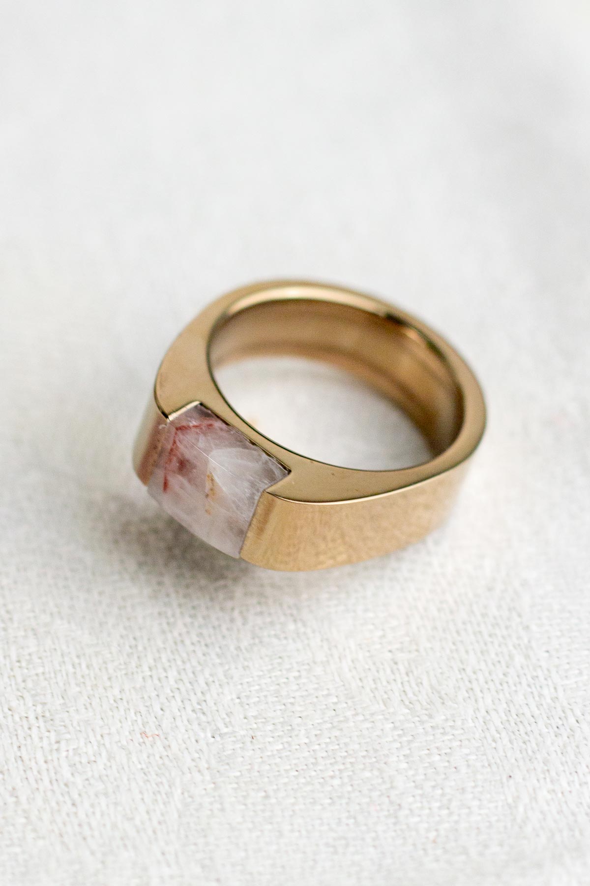 A pink quartz rock inset into a chunky champagne color stainless steel ring
