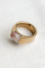 A pink quartz rock inset into a chunky champagne color stainless steel ring