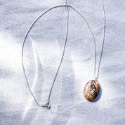 A long sterling silver chain with a brown speckled stone pendant