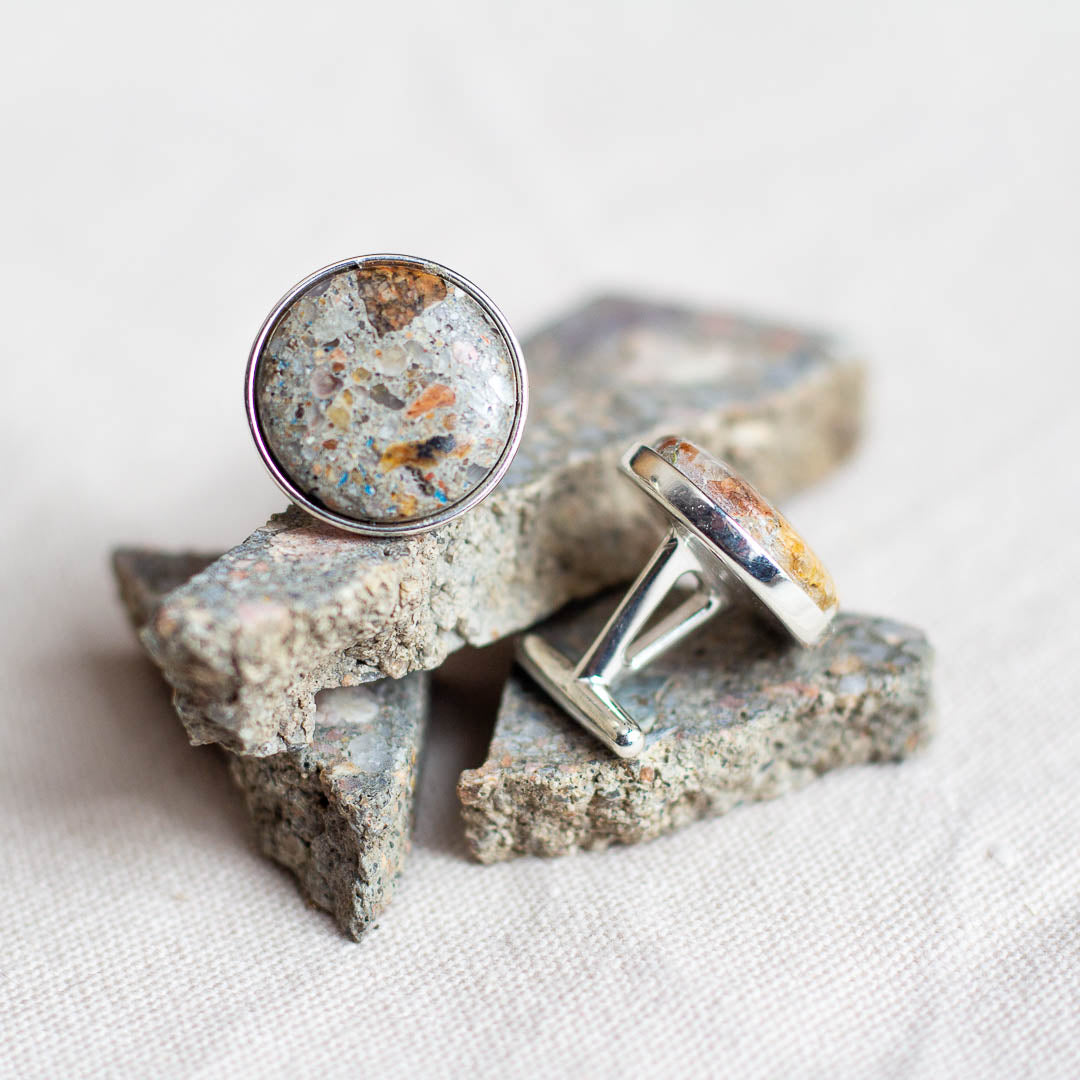 Custom cement cufflinks set in sterling silver sit on top of raw cement that they were made from