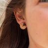 Woman wearing round earrings made of a natural brown stone